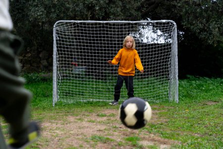 Child goalkeeper waiting to stop a ball that is going towards him
