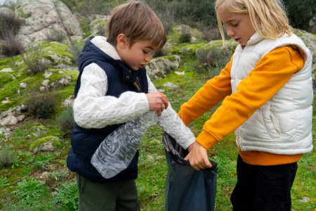 Two children collecting garbage from nature