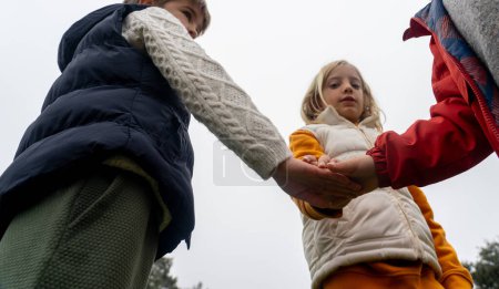 Téléchargez les photos : Une équipe d'enfants met la main ensemble - en image libre de droit