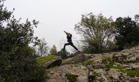 Silhouette of boy jumping between rocks in nature