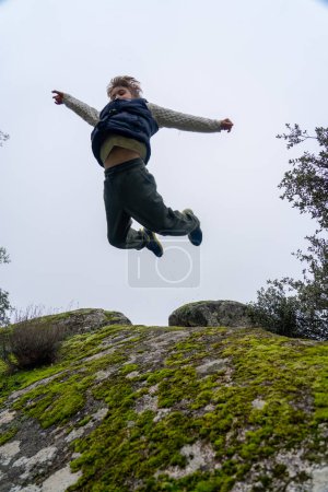 Niño saltando en la naturaleza visto desde abajo