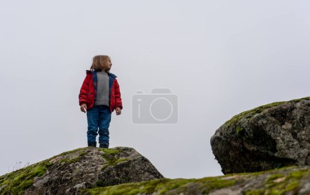 Niño jugando en la naturaleza en algunas rocas grandes