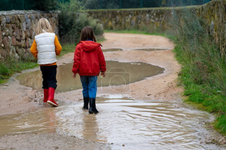 Children walking along a path full of puddles