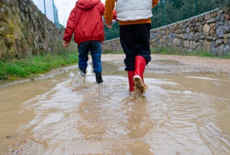 Children walking over a puddle with wellies
