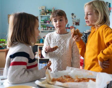 niños comiendo pizza juntos en una cocina