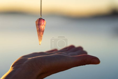 Pendulum over a hand seen up close in nature