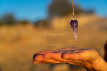 Pendulum over hand in nature