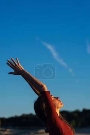 Woman meditating doing yoga with a blue sky in the background