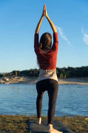 Woman doing yoga looking at a lake in nature