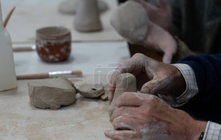 Mains de l'homme âgé apprenant la poterie dans un cours de poterie