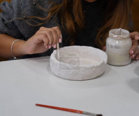 Femme dans une classe de poterie peignant une pièce