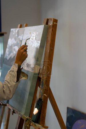 Woman's hand painting on a canvas in a painting workshop