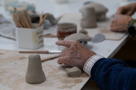 Las manos de un hombre mayor moldeando cerámica en una clase de cerámica