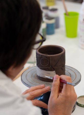Femme peignant un vase en céramique