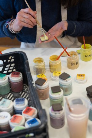 Woman glazing ceramic pieces of different colors to make a color palette