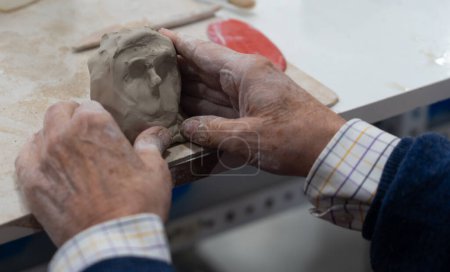 Mains de l'homme âgé faisant une sculpture en argile