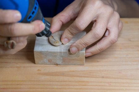 Person macht mit einem Drehwerkzeug ein Loch in einen Stein