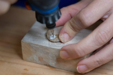 Manos de mujer tallando una piedra con una herramienta rotativa