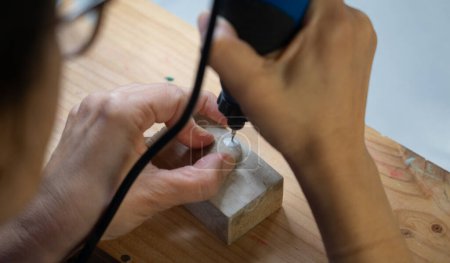 Hände einer Kunsthandwerkerin, die mit einem Drehwerkzeug Stein schnitzt