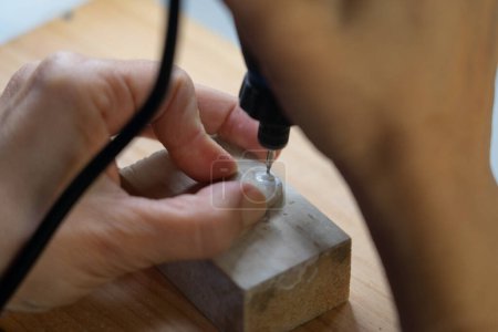 Artisan woman making a hole in a stone to make a necklace