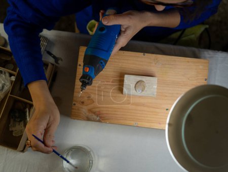 Kunsthandwerkerin schnitzt in ihrer Werkstatt mit einem Drehwerkzeug einen Stein von oben gesehen