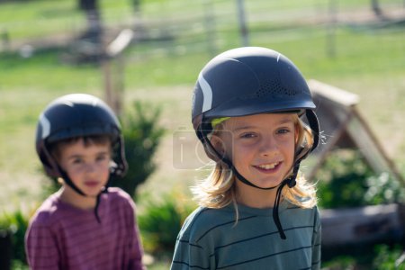 Téléchargez les photos : Deux enfants heureux avec des casques d'équitation - en image libre de droit