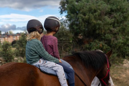 Zwei Kinder auf Pferden spazieren in der Natur