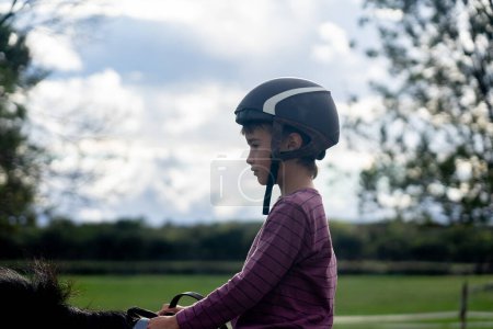 Kind reitet Pferd im Profil