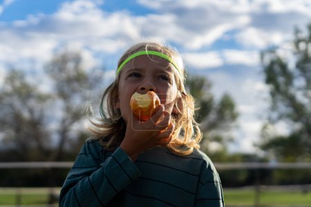 Kind isst einen Apfel im Freien