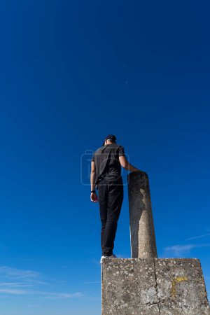 Man climbed on a milestone on top of a mountain