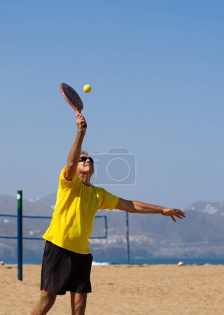 Senior man playing beach tennis. Summer sports