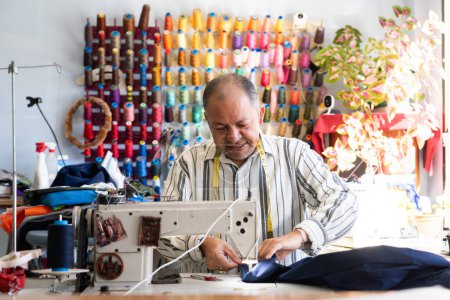 Costurero latino cosiendo con su máquina de coser en su taller de costura