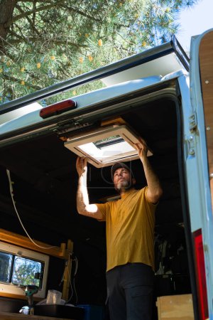 Mann mit Wohnmobil beim Aufstellen einer Dachluke getarnt