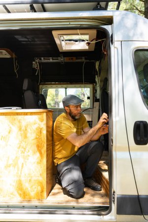 Caucasian man working customizing a camper van putting a thermal insulator on it