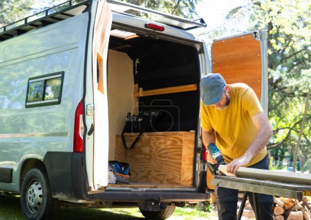 Caucasian man working to camperize his camper van outdoors