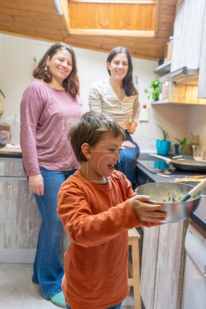 LGBT family of two lesbian mothers and their son cooking together in the kitchen at home