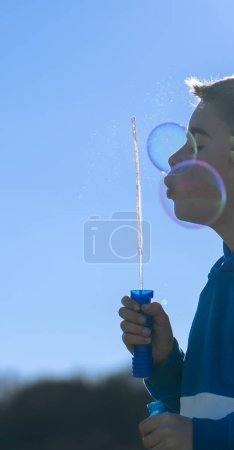 Child blowing a pomeranian making large bubbles seen close up with copy space
