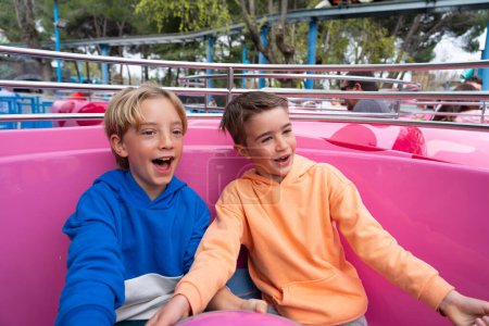 Zwei kaukasische Kinder amüsieren sich auf einer Tassenfahrt in einem Freizeitpark