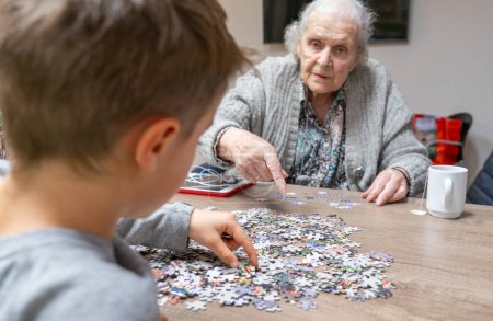 Great-grandmother and her great-grandson doing a puzzle together in a nursing home