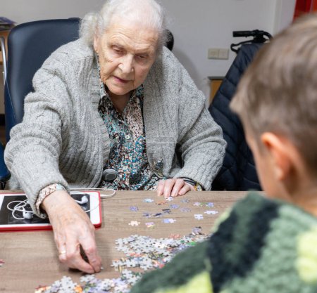 Great-grandmother playing with her great-grandson to do a puzzle together