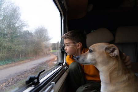 Boy with his dog looking out the window of a motorhome