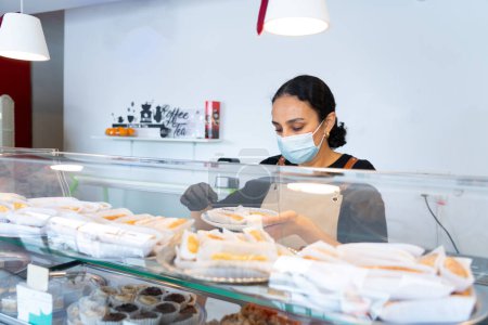 Marokkanerin nimmt Süßigkeiten vom Tresen eines marokkanischen Cafés