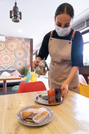 Marokkanische Kellnerin serviert in einem marokkanischen Café einen Minztee