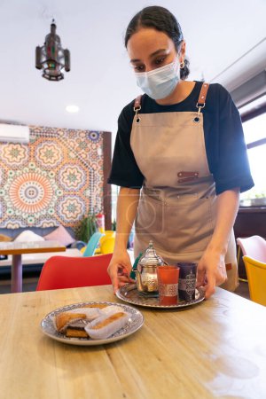 Camarera marroquí sirviendo en una mesa en una tienda de té marroquí