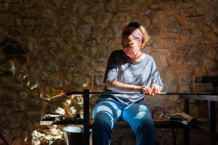Kunsthandwerkerin fertigt in einer Werkstatt ein mundgeblasenes Glasstück