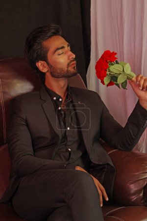 Téléchargez les photos : Jeune homme barbu beau avec une rose rouge à la main - en image libre de droit