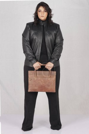 Foto de Una mujer con una chaqueta negra y pantalones negros sosteniendo un maletín marrón - Imagen libre de derechos