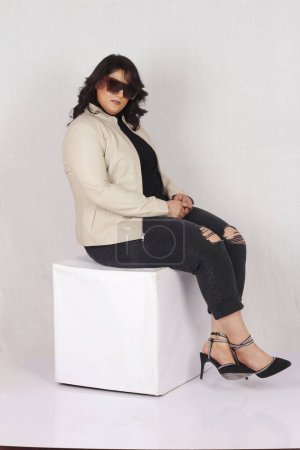 Téléchargez les photos : Une femme assise sur un cube blanc portant des talons noirs - en image libre de droit