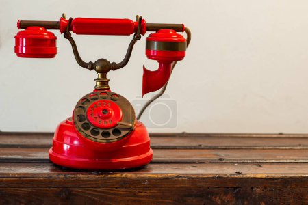 An old red telephone from the last century on a wooden trunk