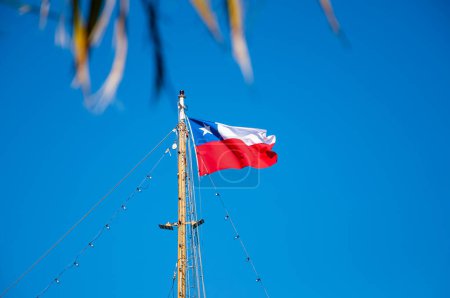 Foto de Bandera de la República de Chile, sobre un mástil, ondeando con el cielo azul como fondo. - Imagen libre de derechos